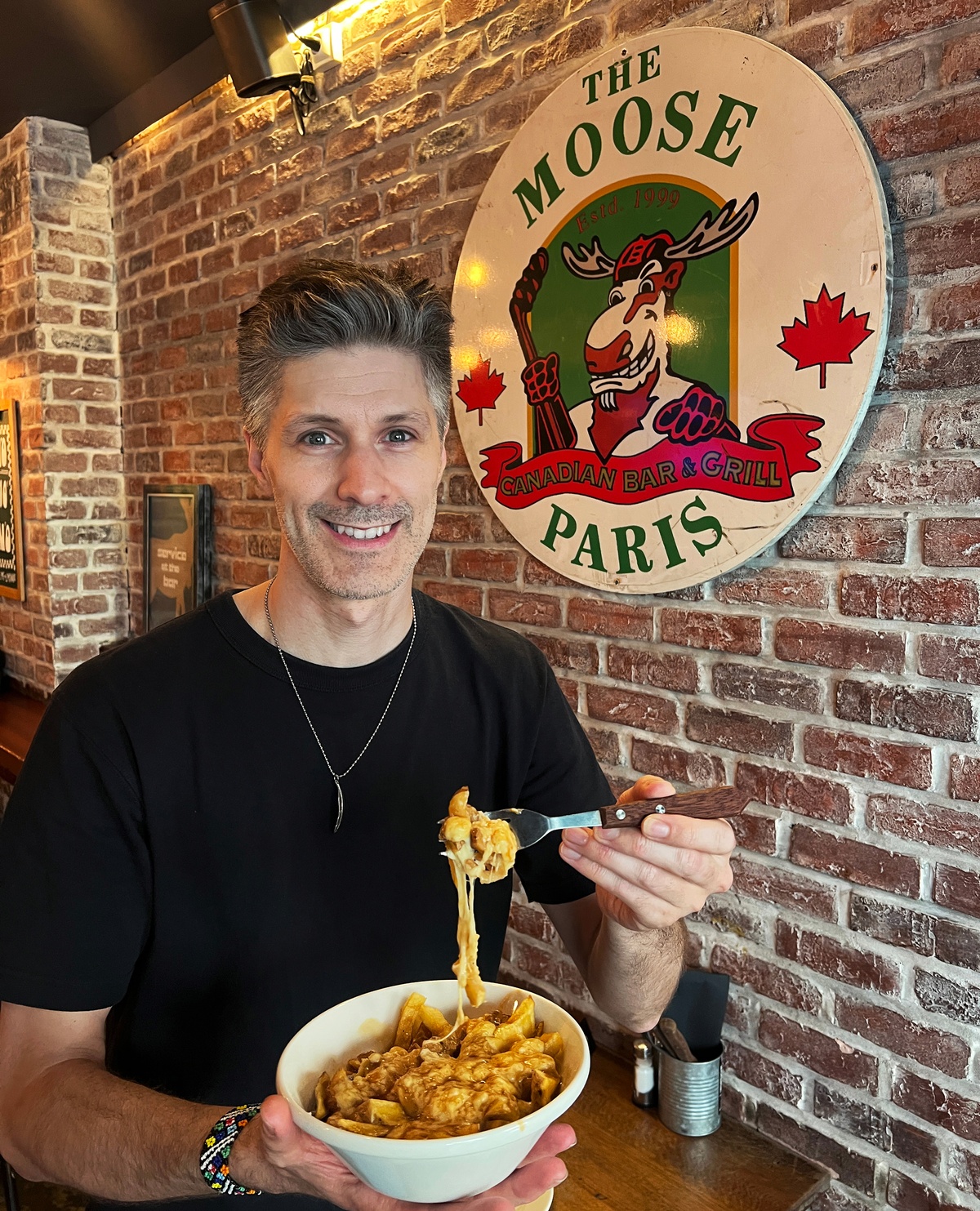 Inside The Moose in Paris holding a poutine