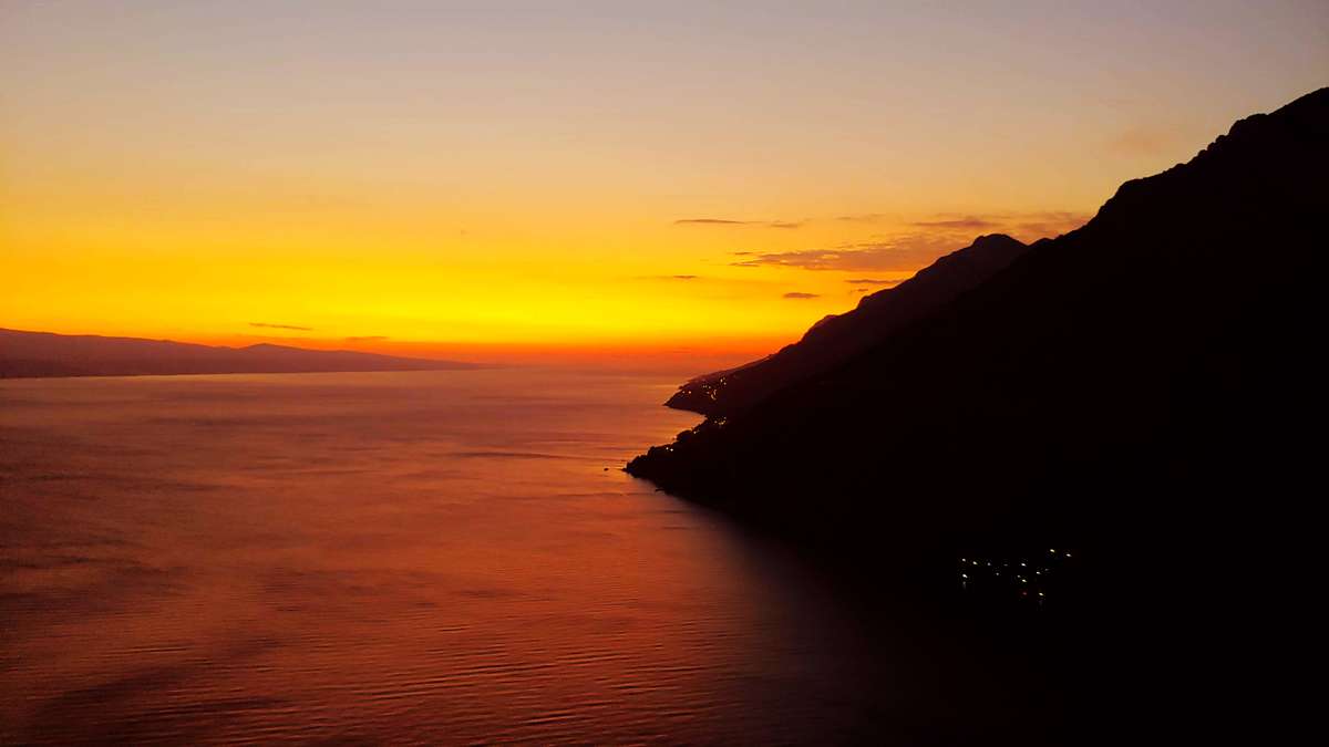 Coucher de soleil orange sur la mer Adriatique avec montagnes et littoral en Croatie