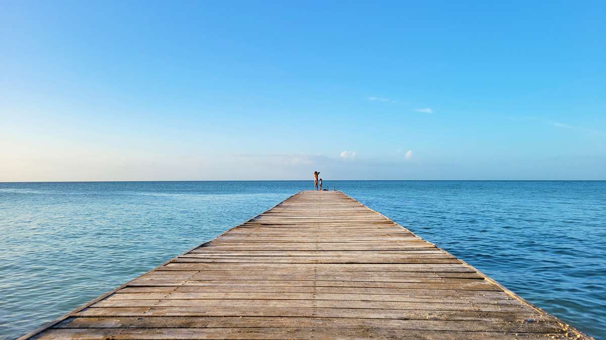 Long wooden pier stretching toward the horizon in Sarteneja, Belize