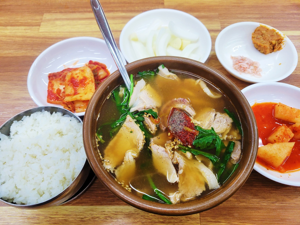 Bowl of gukbap (pork soup) with rice, kimchi, and side dishes