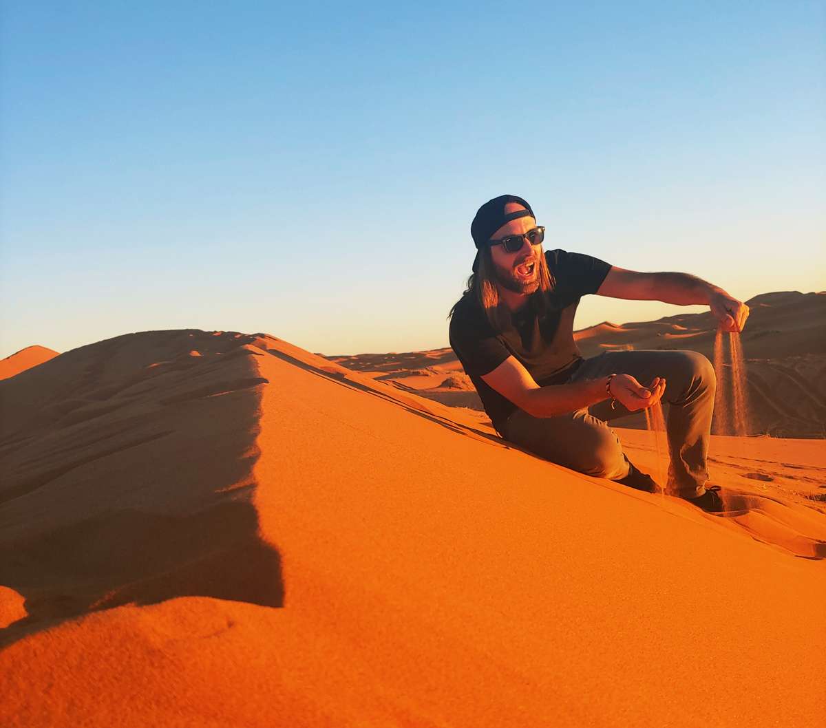 Personne sur une dune de sable à Merzouga au coucher du soleil, Maroc