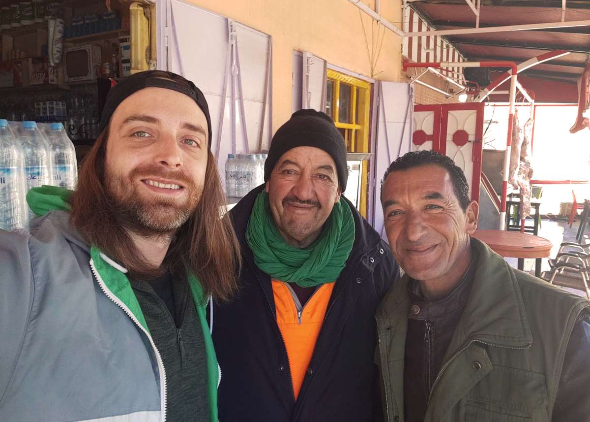Deux habitants et un voyageur devant un hôtel au Maroc
