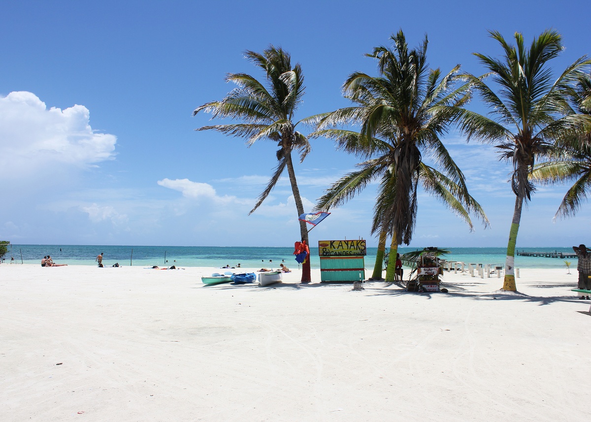 Plage de sable blanc avec eau turquoise et palmiers à Caye Caulker, Belize